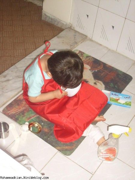 محمدکیان در حال بازی با وسایل اشپزخانه با پیشبند مامان