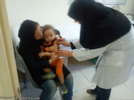 علی تو بغل مامان هنگام واکسن دستش