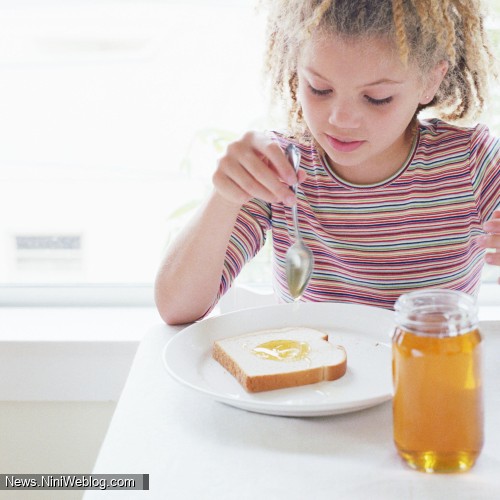 دختر بچه ای در حال خوردن عسل